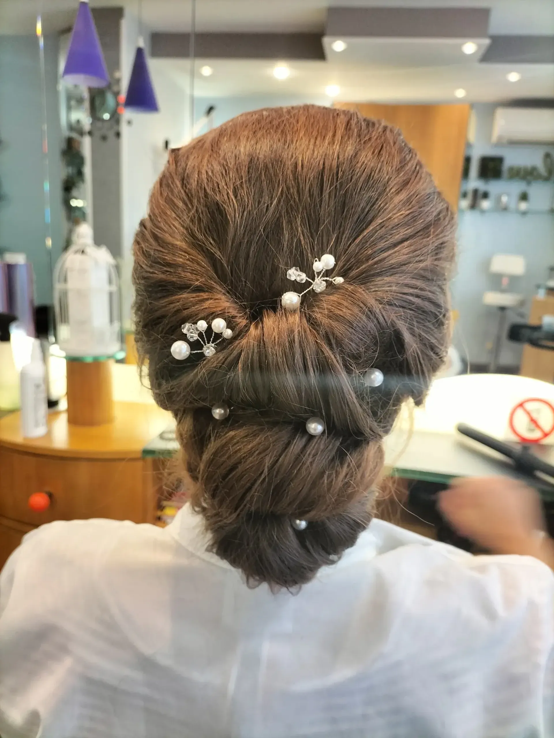 Chignon bas structuré avec épingles perlées, coiffure de cérémonie réalisée au Salon de Muriel à Bordeaux