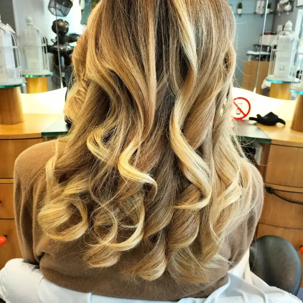 Longs cheveux blonds bouclés avec ombré doré, réalisé au Salon de Muriel à Bordeaux