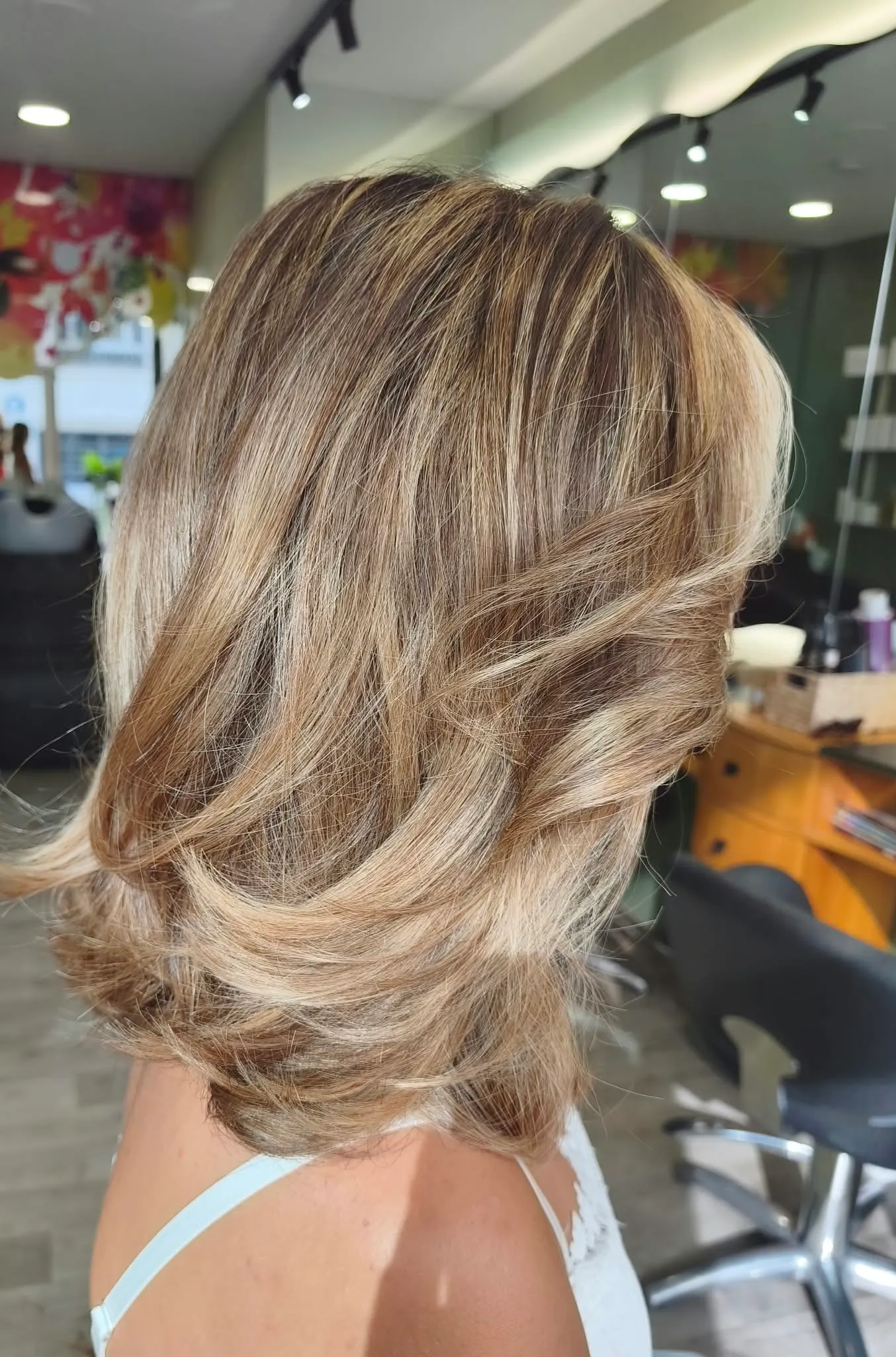 Vue arrière d’un ombré blond très clair beige sur des cheveux mi-longs coiffés en mouvements souples